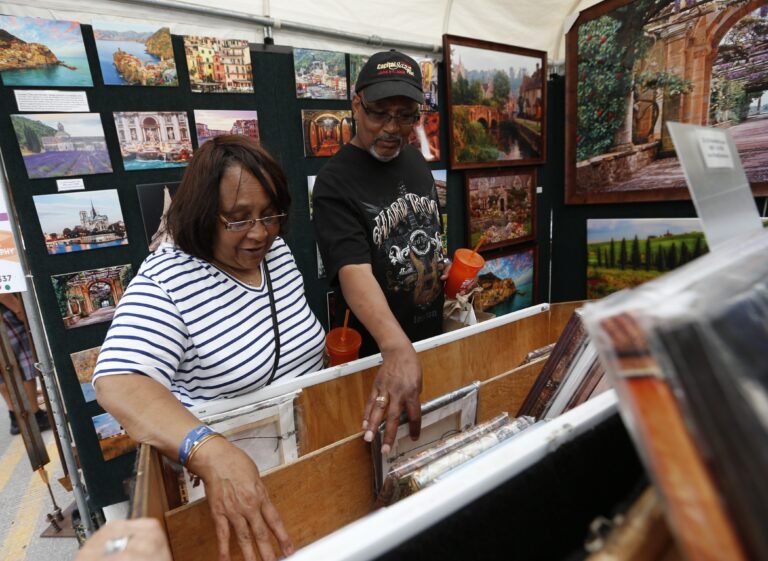 Two Arts Festival attendees browse the selection of prints in a landscape photographer’s booth. Credit: Greg Bartram.
