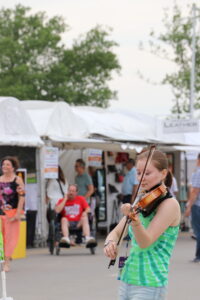 A young violinist busks for tips to fund a trip to Drogheda, Ireland for a prestigious competition. Credit: McKenzi Swinehart.