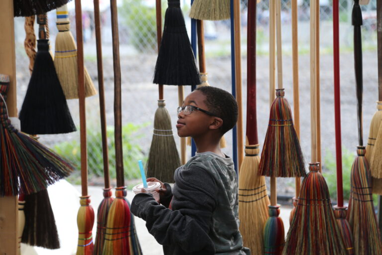 Un jeune acheteur d'art explore le stand d'un écuyer à balais. Crédit : Joe Maiorana.