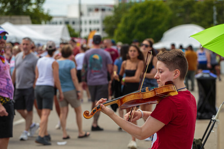 A young violinist busks for tips to fund an upgraded fiddle and grad school tuition. Credit: David Heasley.