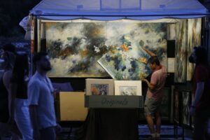 An artist sets up paintings in his booth